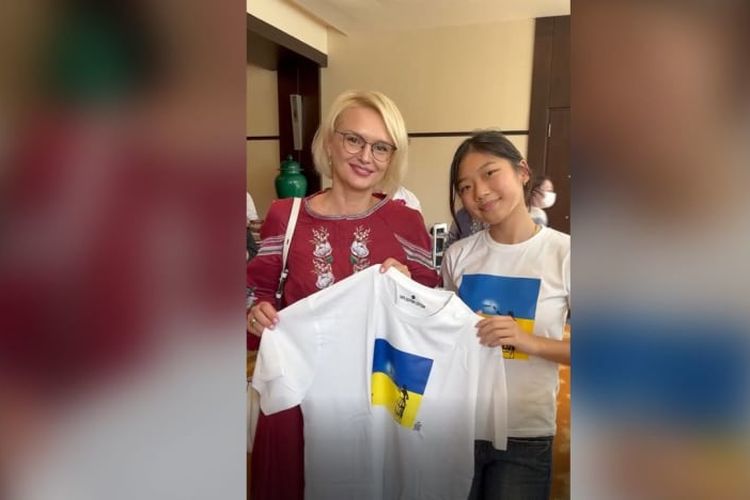 Ava Soh (kanan) berpose dengan desain kaosnya bersama Duta Besar Ukraina untuk Singapura Kateryna Zelenko.