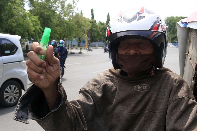 Pengendara motor menunjukkan hand sanitizer yang dibagikan oleh Damma Yanti dan beberapa rekannya di kawasan Pusat Kota Banda Aceh, Minggu (05/04/2020). 500 lembar masker dan 200 botol hand sanitizer yang dibagikan gratis ini menggunakan biaya dari uang tabungan serta menjual cincin emas miliknya.