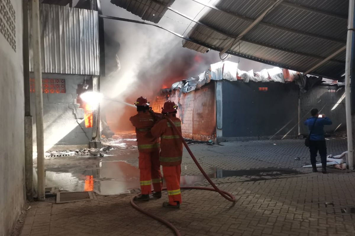 Petugas saat berupaya memadamkan api yang membakar gudang pabrik PT Gunung Agung Sentosa, yang terletak di Desa Kepatihan, Kecamatan Menganti, Gresik, Jawa Timur, Senin (31/7/2023).