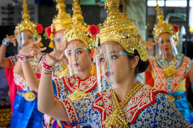 Penari tradisional Thailand yang mengenakan pelindung wajah tampil di Kuil Erawan, yang dibuka kembali setelah pemerintah Thailand melonggarkan langkah-langkah untuk memerangi penyebaran coronavirus novel COVID-19, di Bangkok pada 4 Mei 2020. Thailand mulai melonggarkan pembatasan terkait dengan COVID -19 pada 3 Mei dengan memungkinkan berbagai bisnis untuk dibuka kembali, tetapi memperingatkan bahwa langkah-langkah yang lebih ketat akan diberlakukan kembali jika kasus meningkat lagi.