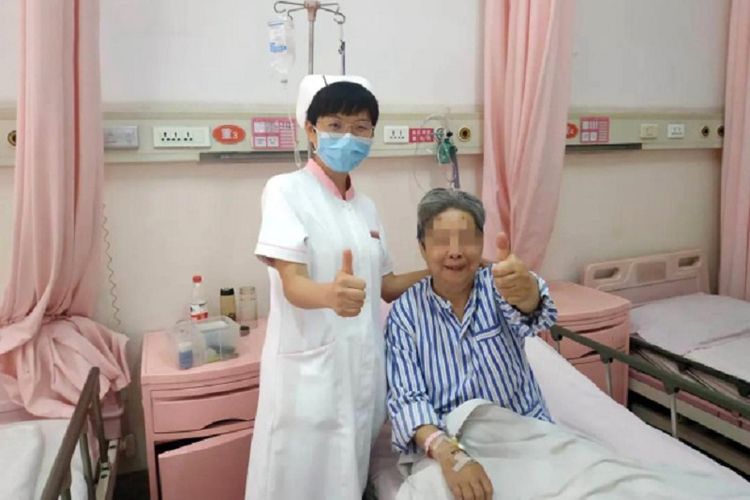 Seorang perempuan 64 bersama perawat di Rumah Sakit Xian Gaoxing, China. Bersama ibunya yang berumur 82 tahun, mereka selamat setelah empat hari terjebak di lift karena meminum air seni.