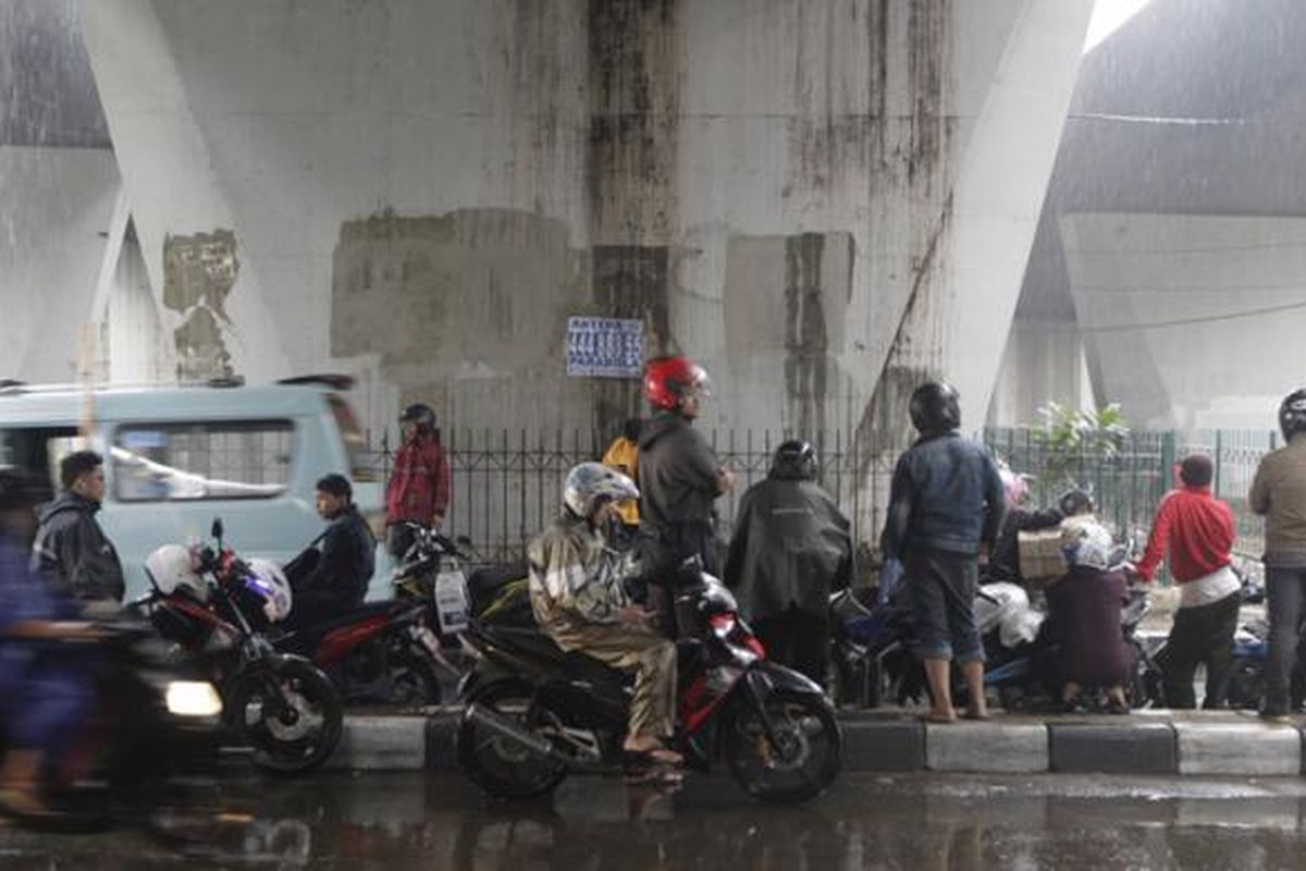 Pengendara motor berteduh di bawah jembatan di kawasan Slipi, Jakarta, Jumat (14/11/2014). Badan Meteorologi, Klimatologi, dan Geofisika (BMKG) memperkirakan wilayah DKI Jakarta diguyur hujan dengan intensitas ringan hingga sedang pada siang hingga malam hari. KOMPAS IMAGES/RODERICK ADRIAN MOZES