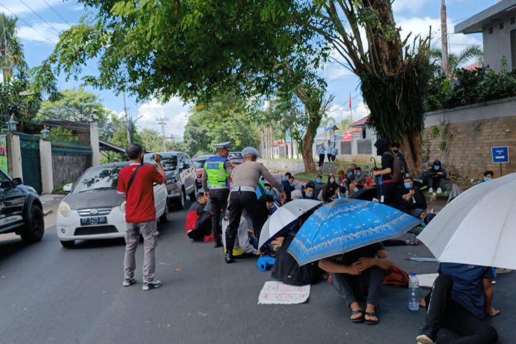 Aparat kepolisian menertibkan pencari suaka yang duduk di badan jalan saat unjuk rasa di depan Rudenim Tanjungpinang.