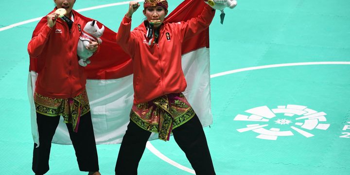 Pasangan pesilat Indonesia peraih medali emas Ayu Sidan Wilantari (kiri) dan Ni Made Dwiyanti (kanan) berpose usai upacara penyerahan medali nomor ganda putri pencak silat seni Asian Games 2018 di Padepokan Pencak Silat Taman Mini Indonesia Indah (TMII), Jakarta, Rabu (29/8/2018).