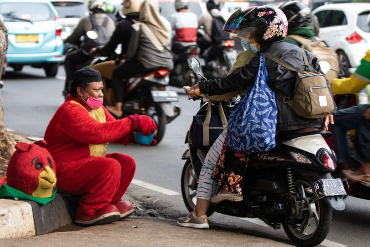 Ahsan Basri Joni mengenakan kostum Angry Bird berharap mendapat sedekah dari pengguna jalan yang lewat di Jalan Gatot Subroto, Jakarta, Selasa (5/1/2021). Kelompok masyarakat rentan, seperti pemulung, gelandangan, pengemis, dan korban PHK adalah kelompok masyarakat yang paling terdampak selama pandemi Covid-19.