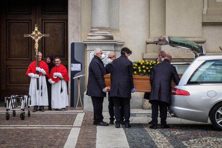 Orang-orang memakai masker saat memghadiri pemakaman di Bergamo, Italia Utara, saat virus corona melanda Italia. Foto diambil pada 7 Maret 2020.