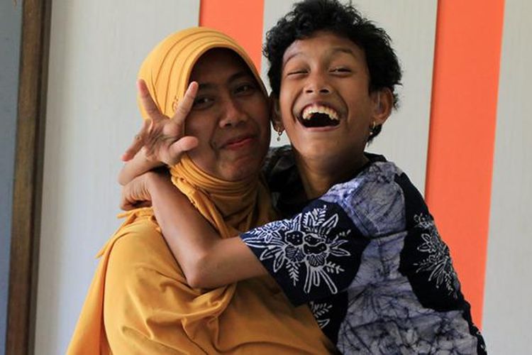 Sri Agustina Imawati (kanan) menggendong Sofi yang menderita cerebral palsy sejak kecil.