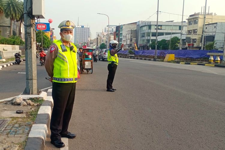 Polisi mengawasi jalannya aturan Ganjil Genap DKI Jakarta di jalan gajah Mada