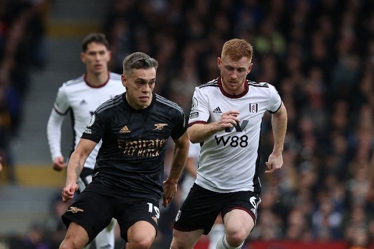 Leandro Trossard (kiri) berebut bola dengan Harrison Reed (kanan) dalam laga pekan ke-27 Liga Inggris 2022-2023 antara Fulham vs Arsenal di Craven Cottage, 12 Maret 2023. (Photo by ADRIAN DENNIS / AFP)