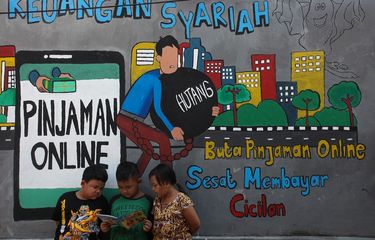 Sejumlah anak membaca bersama di dekat dinding bermural di kawasan Tempurejo, Surabaya, Jawa Timur, Selasa (7/9/2021). Mural tersebut sebagai sarana imbauan kepada masyarakat terhadap bahaya pinjaman daring atau 'online' (pinjol) ilegal yang sekarang lagi marak. ANTARA FOTO/Didik Suhartono/hp.