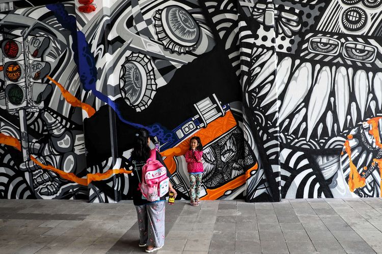 Warga melintasi mural karya dari seniman asal Berlin, Jerman Snyder di terowongan Jalan Kendal, Jakarta Pusat, Senin (29/7/2019). Tema Mural yaitu Persahabatan untuk perayaan 25 tahun hubungan antara Jakarta dan Berlin sebagai Sister City.