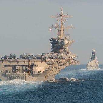 Kapal induk USS Abraham Lincoln (kiri) saat berlayar di Selat Hormuz pada 19 November 2019. Amerika Serikat mengerahkan kapal yang biasanya mangkal di Pasifik Barat ini untuk mendekat ke Iran, di tengah tensi kedua negara yang semakin memanas.