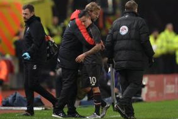 Manajer Liverpool, Juergen Klopp (merah) memberikan pelukan saat Philippe Coutinho ditarik keluar karena cedera pada babak pertama partai kontra Stokie City, Selasa (5/1/2015).