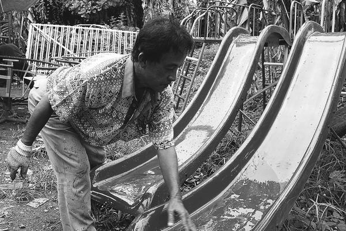 Seorang perajin alat bermain anak dan anak balita menyelesaikan pengecatan papan luncur di bengkelnya.