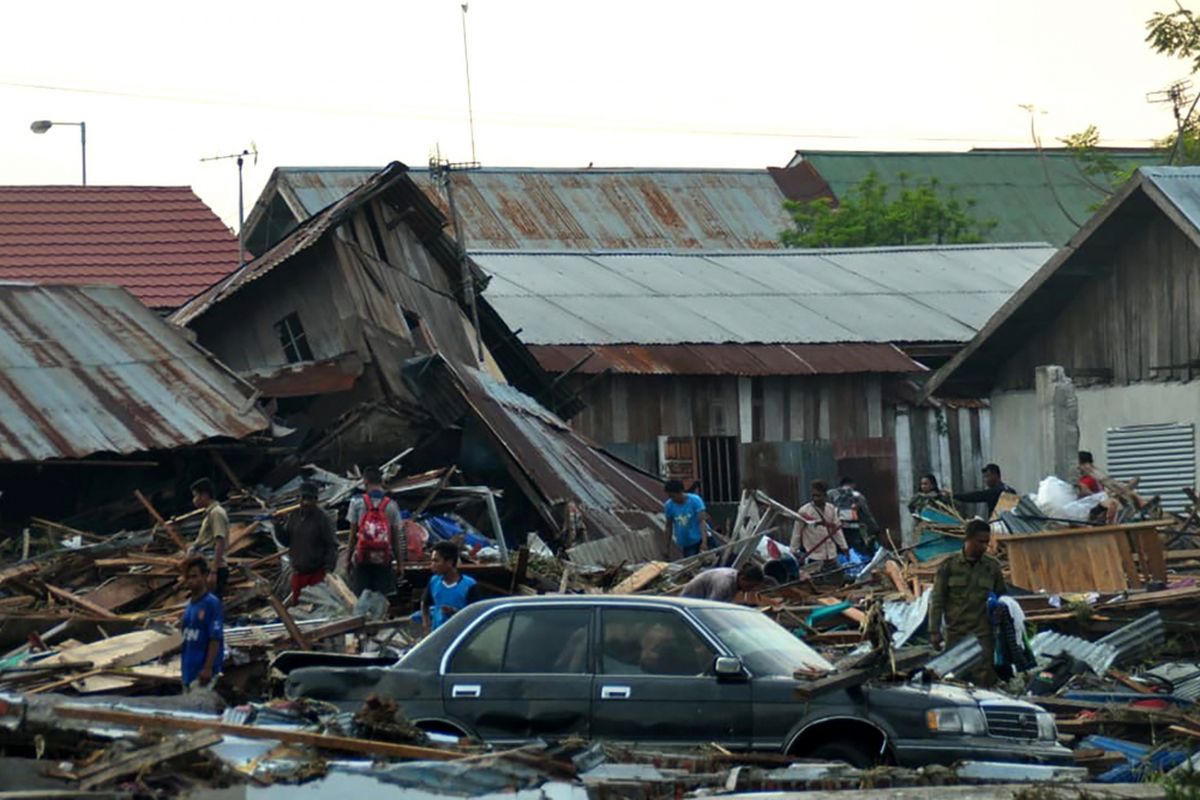 Warga berusaha menyelamatkan barang-barang dari rumah mereka yang runtuh akibat gempa bumi dan tsunami menghantam Palu, Sulawesi Tengah, Sabtu (29/9/2018). Hampir 400 orang tewas akibat gempa yang disusul tsunami pada Jumat (28/9/2018).