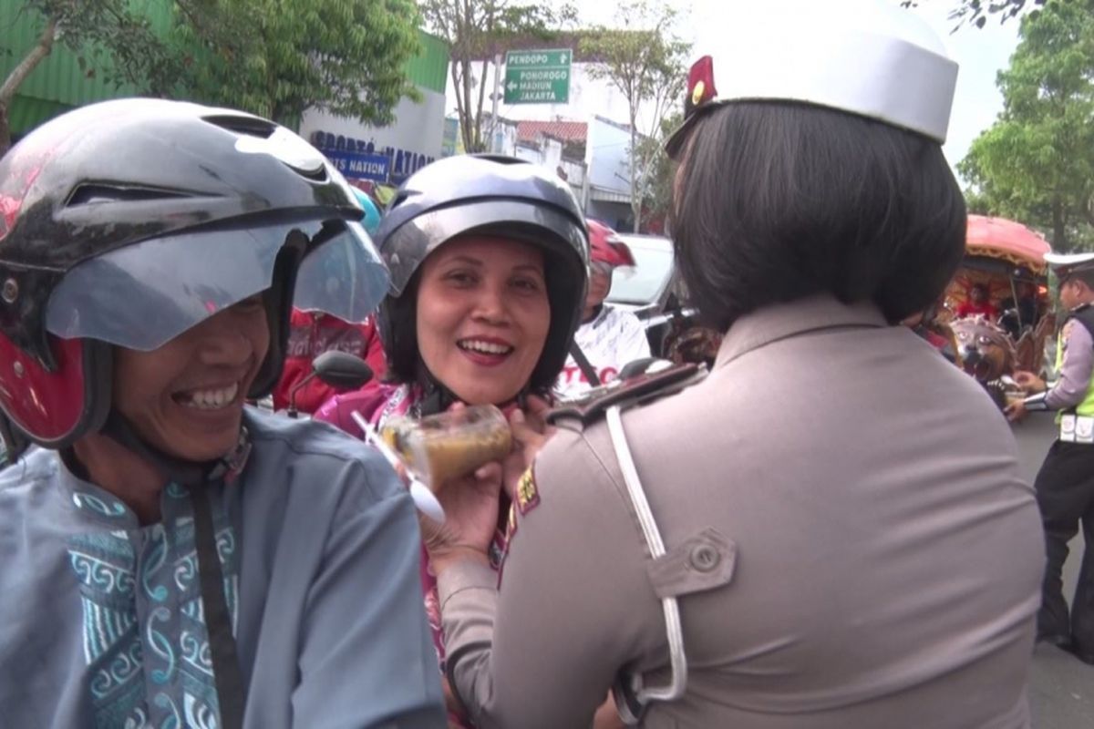 Salah satu polisi wanita mengancingkan tali helm pengaman pengendara,sambil membagikan takjil berbuka puasa (31/05/2017)
