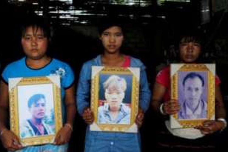 Para perempuan ini membawa foto keluarga mereka yang tewas dibunuh tentara Myanmar pada Juni lalu.