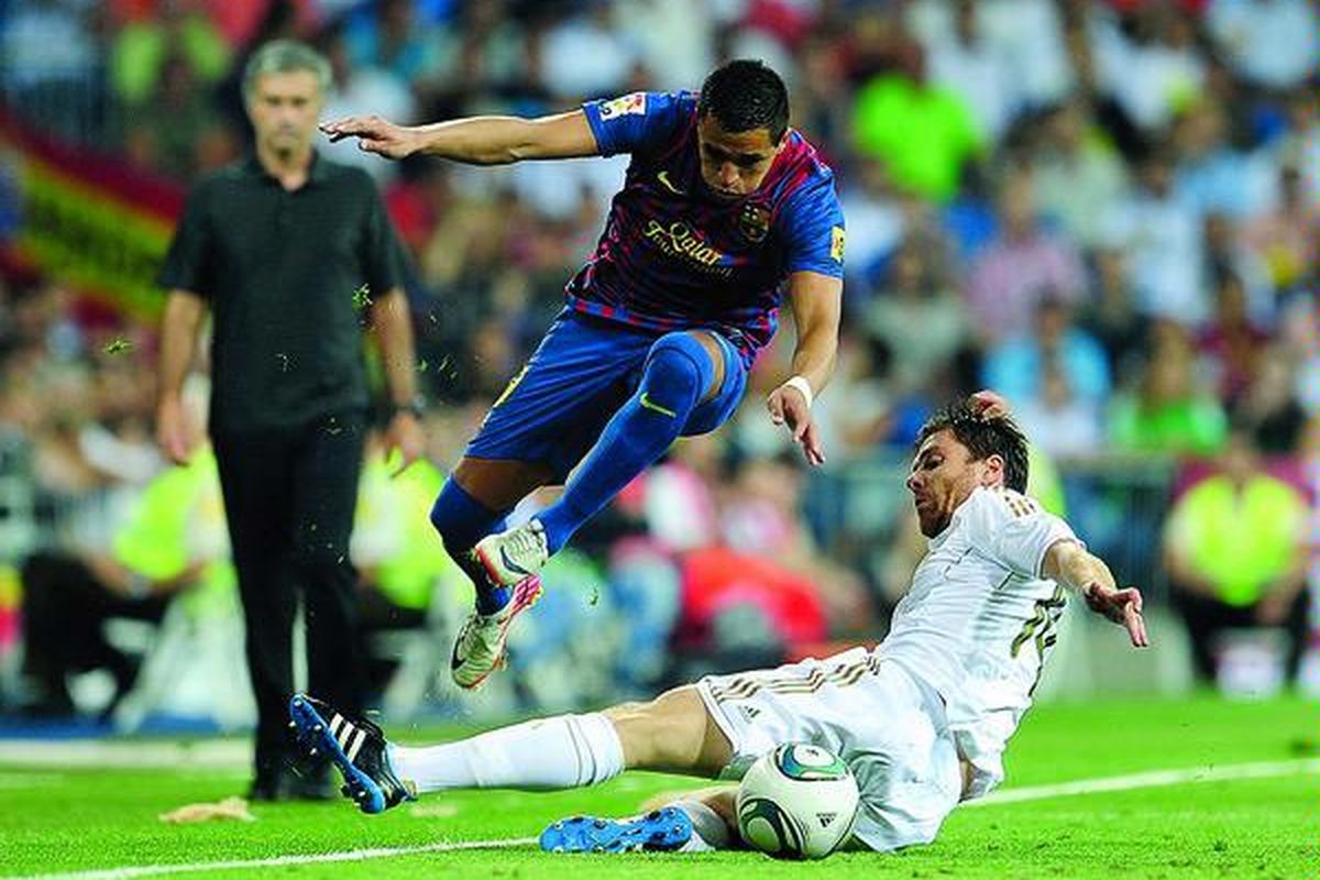 Penyerang baru Barcelona asal Cile, Alexis Sanchez (kiri), lolos dari sergapan gelandang Real Madrid,  Xabi Alonso, pada laga pertama Piala Super Spanyol di Stadion Santiago Bernabeu, Madrid, Spanyol, Minggu (14/8).