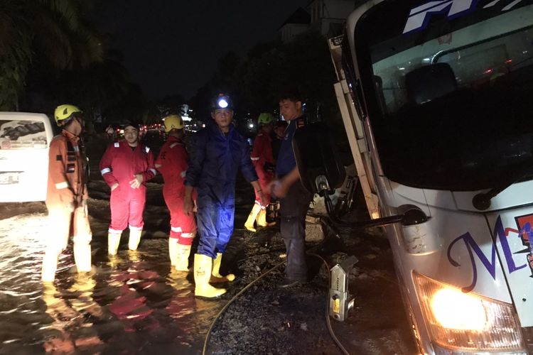 Anggota Damkar Kota Depok membantu proses evakuasi truk muatan pasir yang terperosok di Jalan Boulevard Grand Depok City, Kalimulya, Cilodong, Kota Depok, Jawa Barat pada Senin (6/12/2021) malam