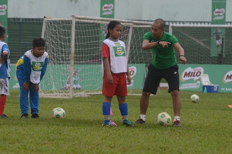 Kurniawan Dwi Yulianto sedang memberikan pelatihan teknik dasar sepak bola pada MILOFootball Clinic Day Bandung, seperti dribbling, passing, controlling, shooting, dan keeping.