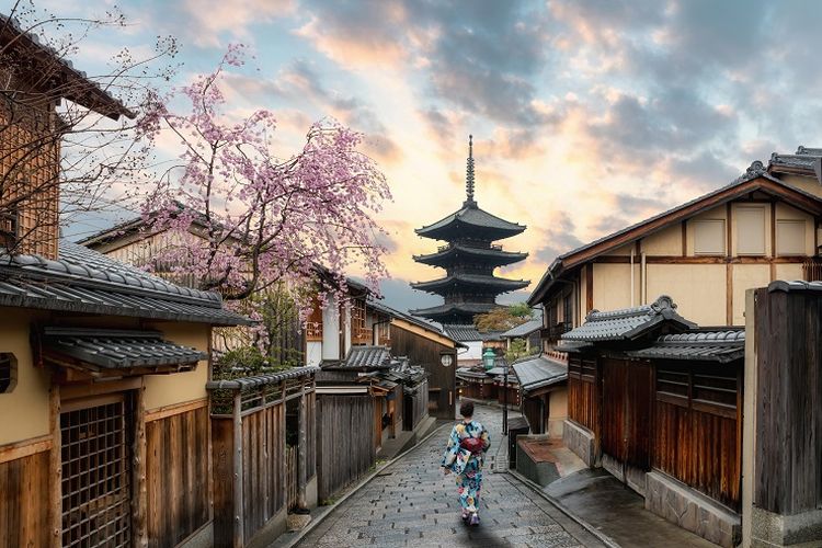 Seorang wanita mengenakan pakaian tradisional Jepang sedang berjalan-jalan di Kyoto, Jepang.