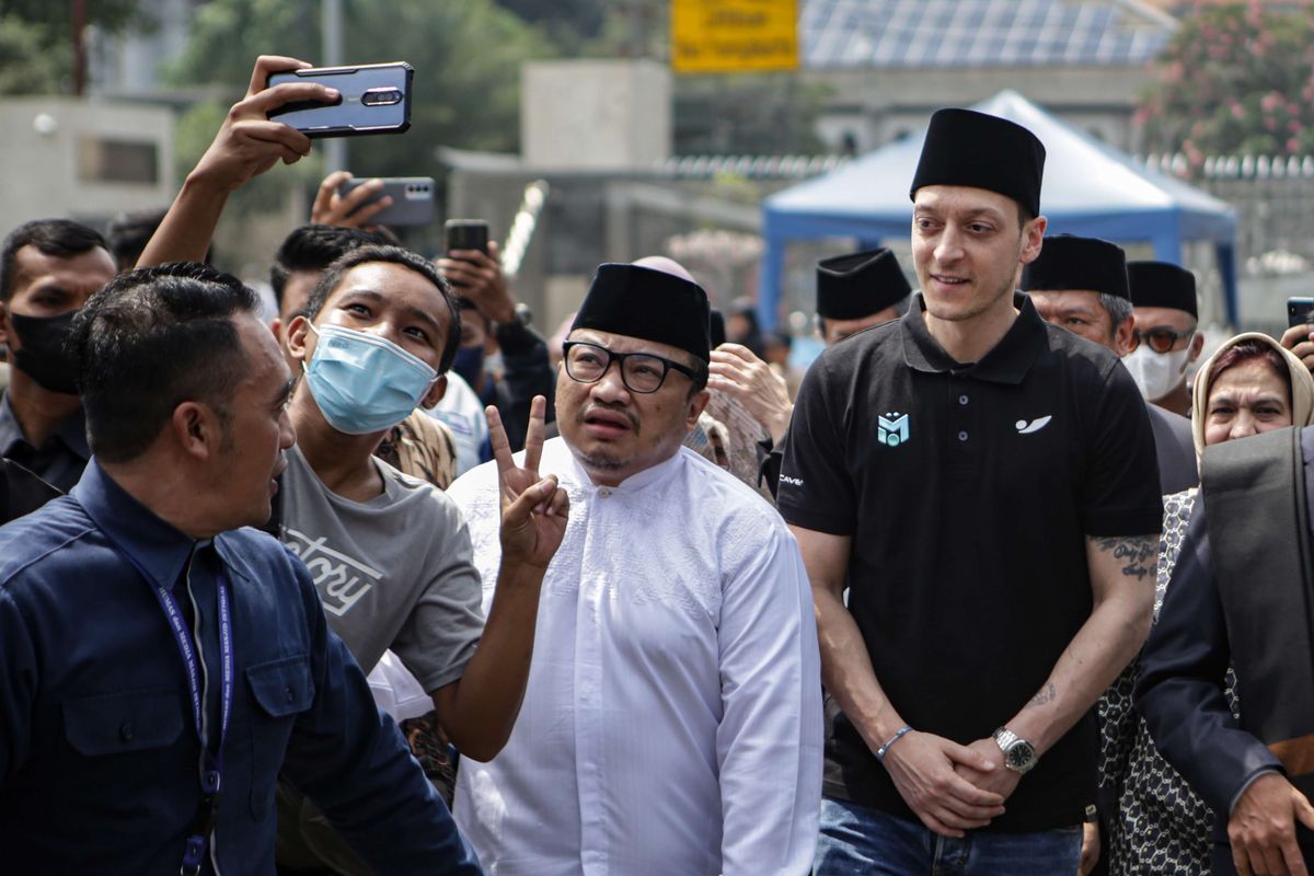 Pesepak bola klub Fenerbahce SK Mesut Oezil (kanan) melayani swafoto warga setibanya di Masjid Istiqlal, Jakarta, Jumat (27/5/2022). Dalam kunjungannya ke Indonesia, Mesut Oezil menyempatkan untuk melaksanakan Shalat Jumat di Masjid Istiqlal.