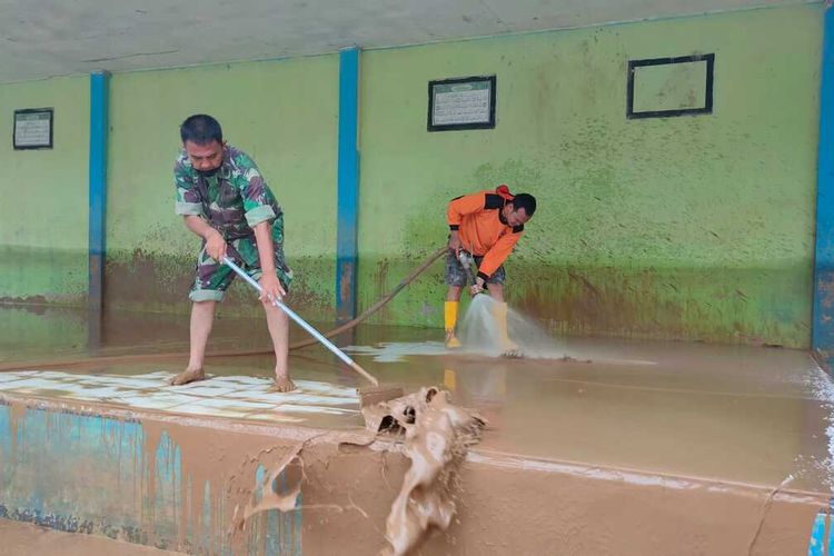 Prajurit TNI dan anggota BPBD Rokan Hulu membersihkan lumpur yang memenuhi sebuah sekolah madrasah pasca banjir di Kecamatan Rambah, Kabupaten Rokan Hulu, Riau, Minggu (2/1/2022).