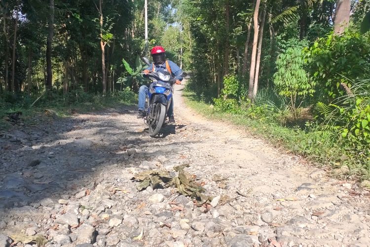 Warga melewati jalan batu yang berserakan di kawasan Pedukuhan Watu Belah, Kalurahan Sidomulyo, Kapanewon Pengasih, Kabupaten Kulon Progo, Daerah Istimewa Yogyakarta.
