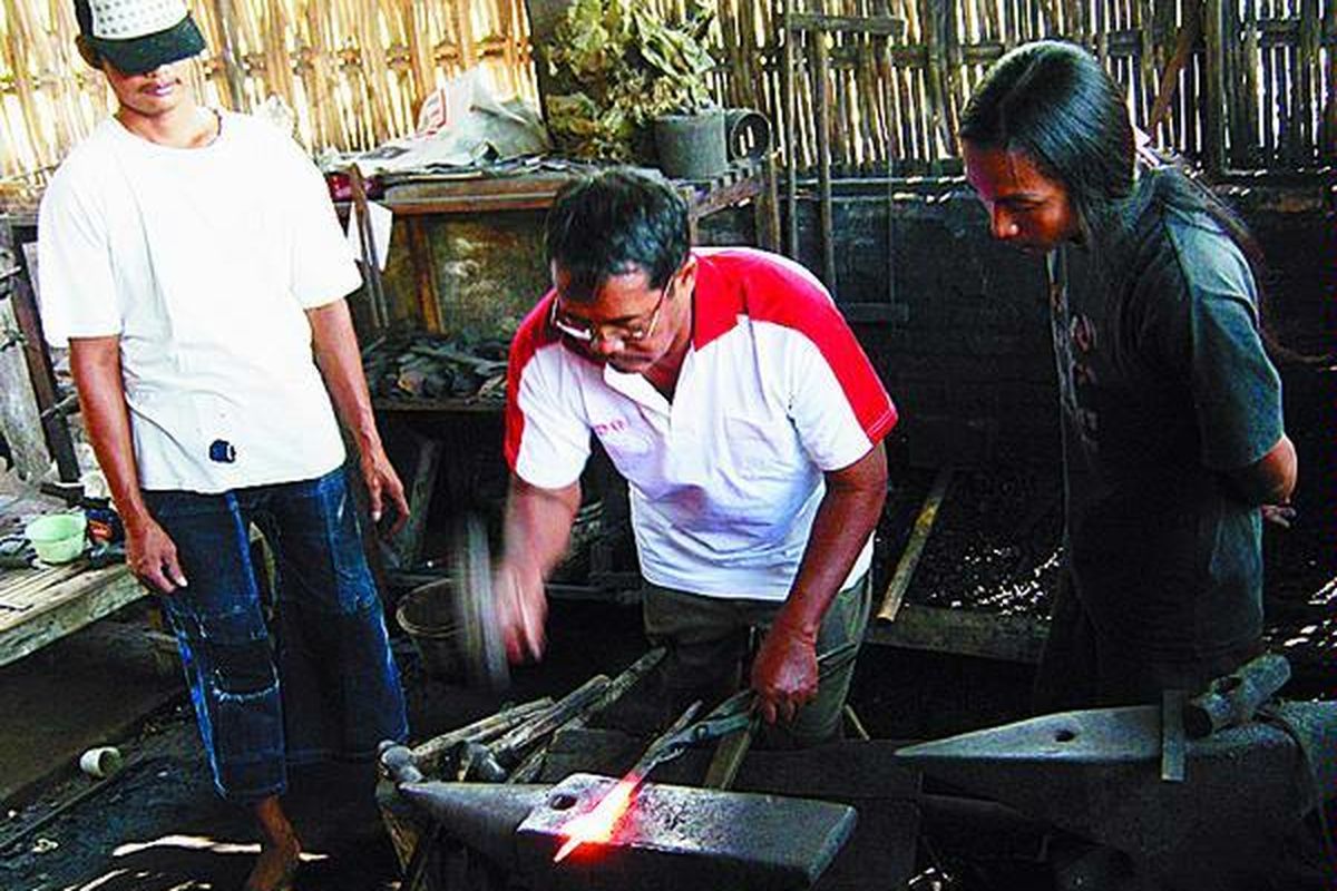 Sigit (kanan), mahasiswa Institut Seni Indonesia, belajar membuat keris dari Empu Subandi (tengah) dan asistennya, Sukimin di Solo, Jumat (8/8)..  