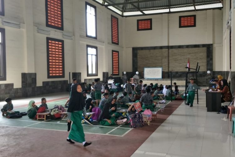 Tampak ratusan siswa SDN 01 Cicau, Kecamatan Cikarang Pusat, Kabupaten Bekasi belajar di GOR Kantor Desa Cicau karena atap dua ruang kelas roboh, Kamis (7/2/2019).