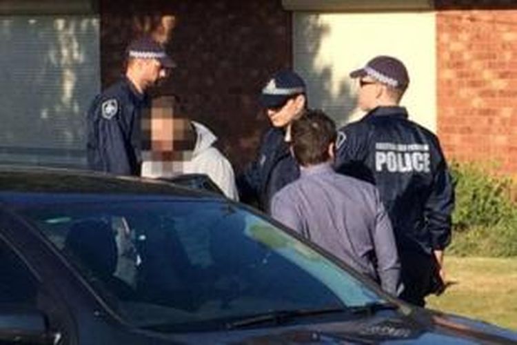 Seorang pria dimasukan kedalam mobil polisi di luar rumah yang digeledak polisi di pinggiran kota Melbourne.