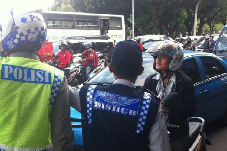 Pengendara motor bertanya kepada petugas jalan menuju tujuannya di hari pertama uji coba pembatasan sepeda motor di Jalan MH Thamrin hingga Jalan Medan Merdeka Barat, Rabu (17/12/2014).