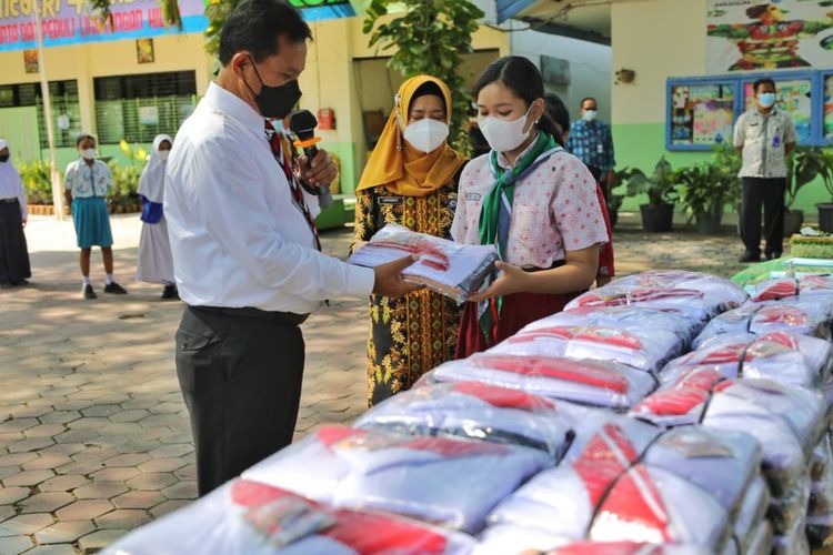 SERAHKAN KAIN-Walikota Madiun, Maidi memberikan kain seragam gratis bagi siswa kelas 1 SD dan kelas 7 SMP beserta ongkos jahit di SMPN 4 Kota Madiun, Kamis (7/10/2021).