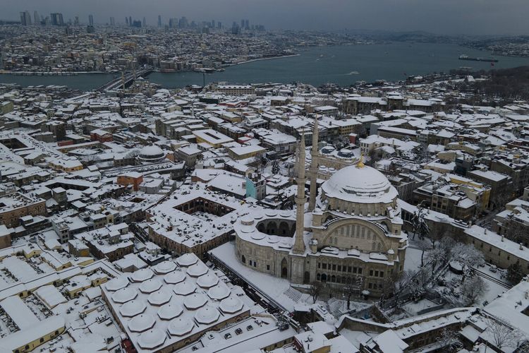 Salju menutupi atap dan masjid Nuruosmaniye, kanan, setelah hujan salju lebat di Istanbul, Turki, Selasa, 25 Januari 2022. 