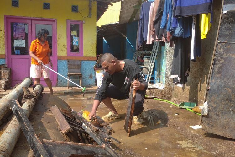 Heri Heriawinata (52) dan istrinya masih membersihkan sisa lumpur akibat pipa PDAM Tirtawening, Kota Bandung, Jawa Barat yang pecah, Selasa (11/6/2024).