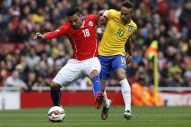 Striker Brasil, Neymar (kanan), berebut bola dengan bek Cile, Gonzalo Jara (kiri), pada laga persahabatan di Stadion Emirates, London, Minggu (29/3/2015).