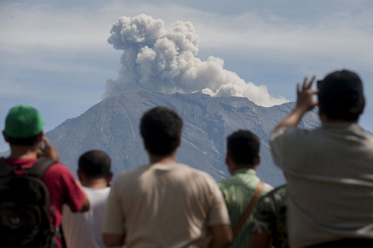 Sejumlah warga menyaksikan asap disertai abu vulkanis keluar dari kawah Gunung Agung yang masih berstatus awas, di Pos Pengamatan Gunung Api Agung, Desa Rendang, Karangasem, Bali, Sabtu (9/12/2017). Pusat Vulkanologi dan Mitigasi Bencana Geologi sejak Jumat (8/12) mengamati beberapa kali terjadi letusan bersifat efusif sesaat yang disertai hembusan asap dan abu vulkanis hingga ketinggian 2.000 meter dari kawah Gunung Agung.