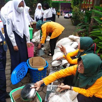 Siswa dibantu guru mengumpulkan alat untuk pengomposan.