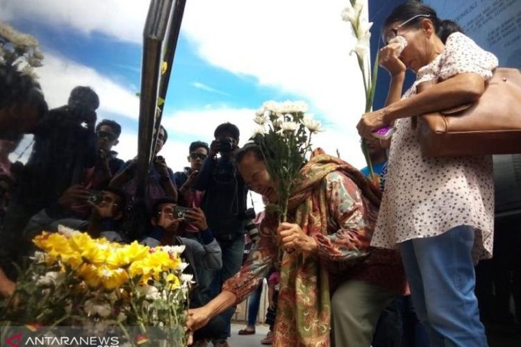Keluarga korban letakkan bubga tangkai di monumen kapal tenggelam di Desa Tigaras Kabupaten Simalungun. 
