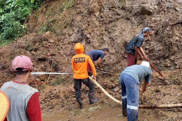 Tim gabungan membersihkan material longsor yang menutup akses jalan Dusun Karanggondang, Desa Sambirata, Kecamatan Cilongok, Kabupaten Banyumas, Jawa Tengah, Kamis (14/7/2022).