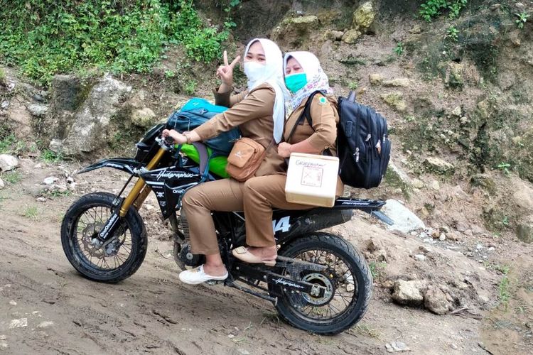 Bidan Dewi bersama rekan sejawatnya di atas motor trail saat menjalankan tugas memberikan layanan kesehatan di pelosok Cianjur, Jawa Barat.