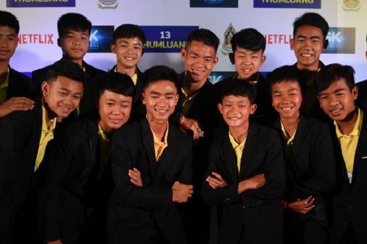 Anggota tim sepak bola Wild Boars berpose untuk berfoto dengan pelatih mereka Ekkapol Chantawong (belakang tengah) selama konferensi pers di Bangkok, Thailand, Selasa (30/4/2019) setelah menandatangani kesepakatan dengan Netflix. (AFP/Lilian Suwanrumpha)
