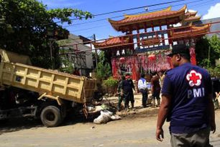 Relawan PMI Sulut dan anggota TNI membantu mengangkat sampah dan lumpur sisa banjir bandang di Kawasan Kampung Cina Manado.