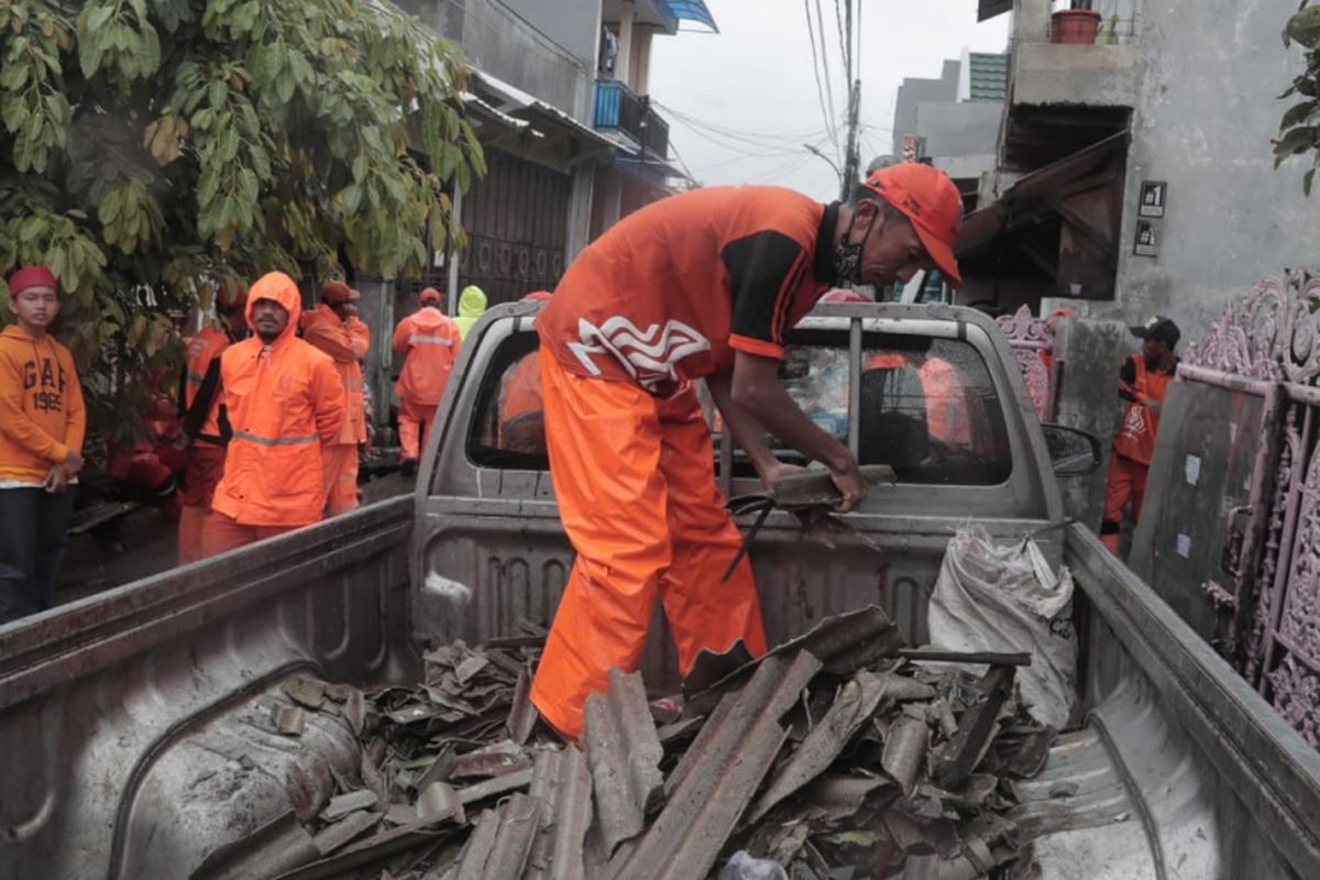 Petugas PPSU mengangkut puing-puing asbes dan genteng ke dalam mobil bak di Lagoa, Jakarta Utara, Jumat (25/1/2019).