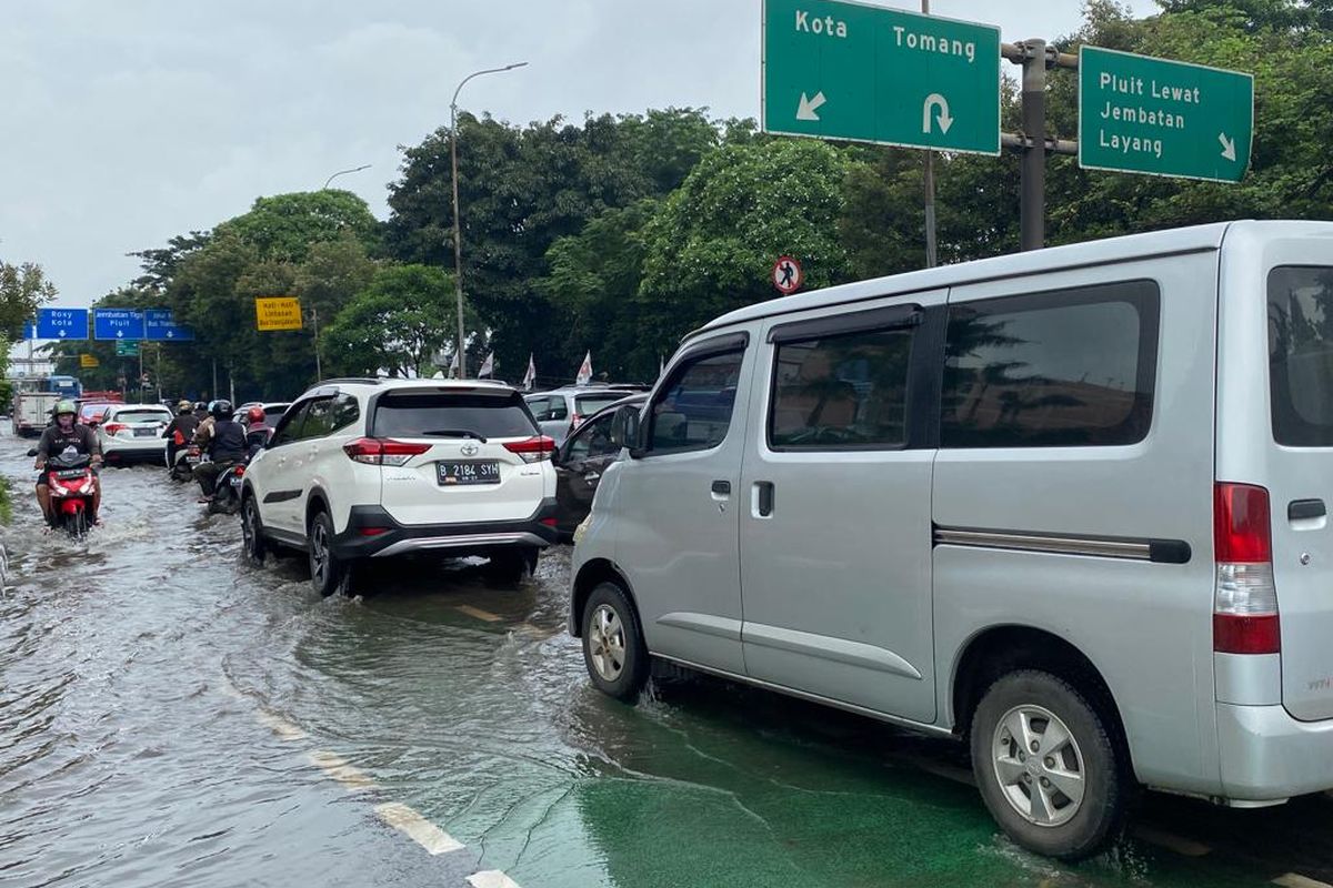 Banjir merendam ruas Jalan Letjen S Parman, Jakarta Barat pada Jumat (24/2/2023). Pengendara sepeda motor dan mobil tetap nekat melintasi kawasan ini. 
