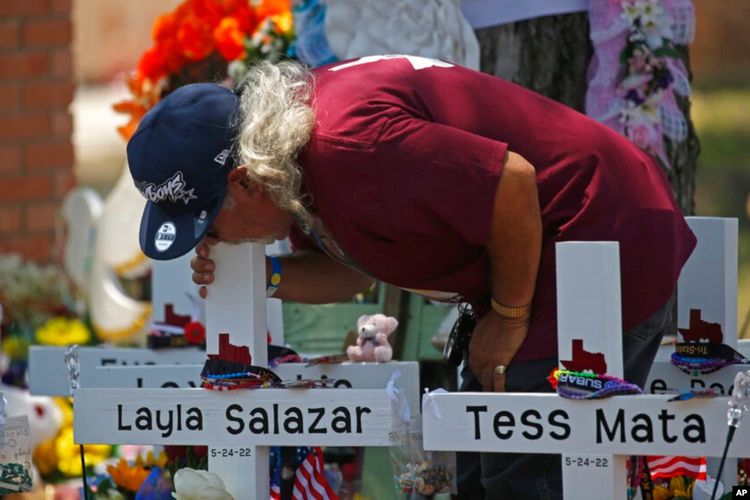 Seorang pria mencium salib Layla Salazar di luar Sekolah Dasar Robb untuk menghormati para korban yang tewas dalam penembakan di sekolah minggu ini di Uvalde, Texas, AS, Sabtu (28/5/2022).