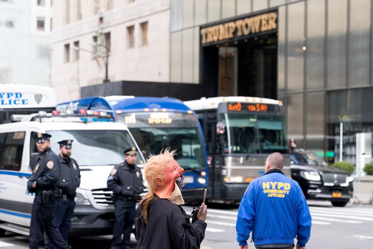 Seorang pengunjuk rasa berdiri di dekat polisi di luar Trump Tower di New York pada 3 April 2023. Donald Trump tiba di gedung pencakar langitnya di New York sebelum dia akan menyerahkan diri untuk menghadapi tuduhan kriminal yang belum pernah terjadi sebelumnya yang mengancam akan mengacaukan seluruh pemilihan Gedung Putih tahun 2024. Republikan berusia 76 tahun, presiden AS pertama yang didakwa secara pidana, akan secara resmi didakwa pada 4 April 2023 atas uang suap yang dibayarkan kepada bintang porno selama pemilu 2016 yang membawanya ke tampuk kekuasaan. 