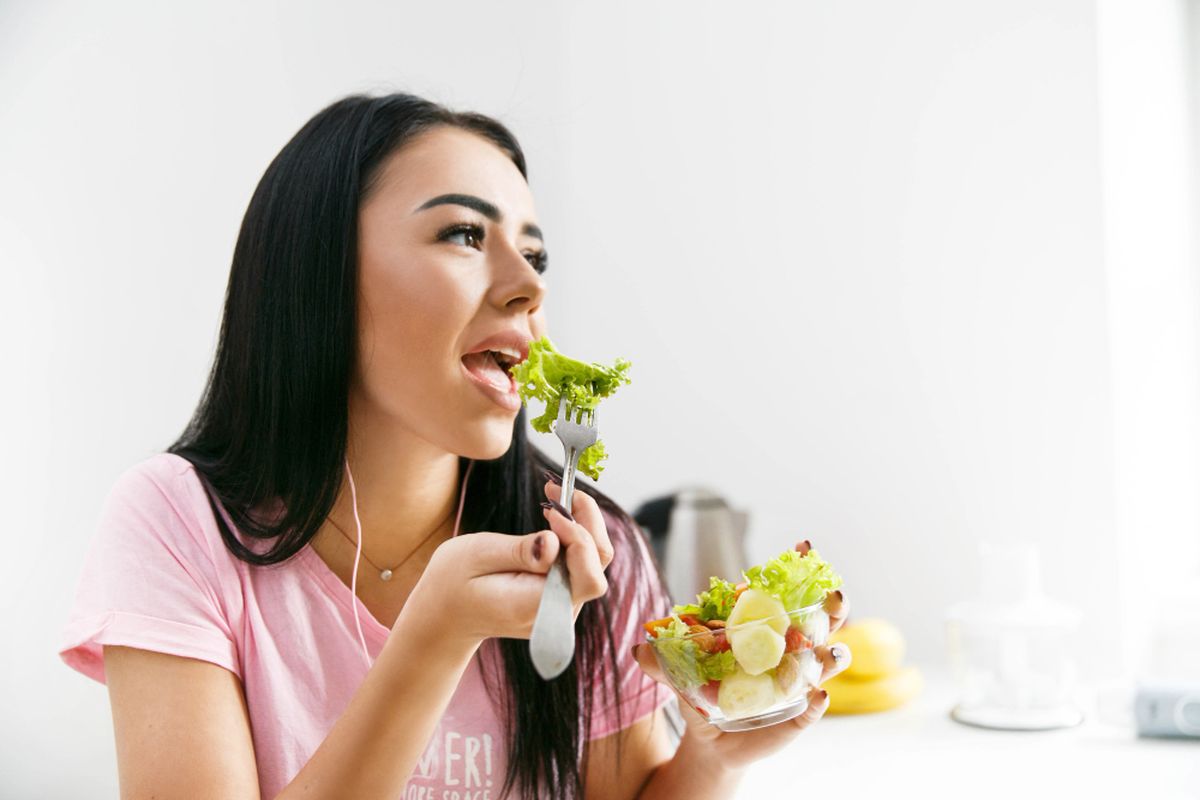 Ilustrasi wanita sedang memakan sayuran.