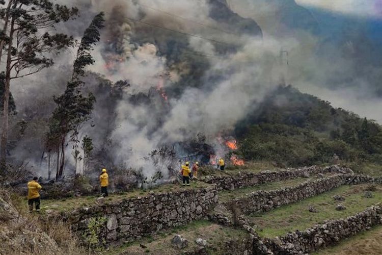 Gambar selebaran yang dirilis oleh Kotamadya Machu Picchu menunjukkan petugas pemadam kebakaran bekerja memadamkan api di semak-semak di sekitar reruntuhan Llamakancha, sebuah sektor di situs arkeologi Machu Picchu, permata Inca dari industri perjalanan Peru, di dataran tinggi dekat dengan kota Cusco, pada 28 Juni 2022.