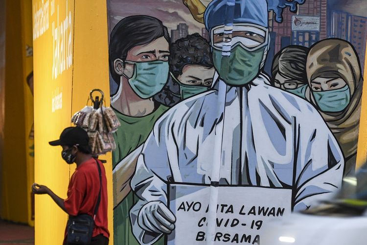 A vendor in Jakarta walks past a mural calling on the public to combat the COVID-19 di Jakarta, Sunday, (29/11/2020).  ANTARA FOTO/M Risyal Hidayat/aww.